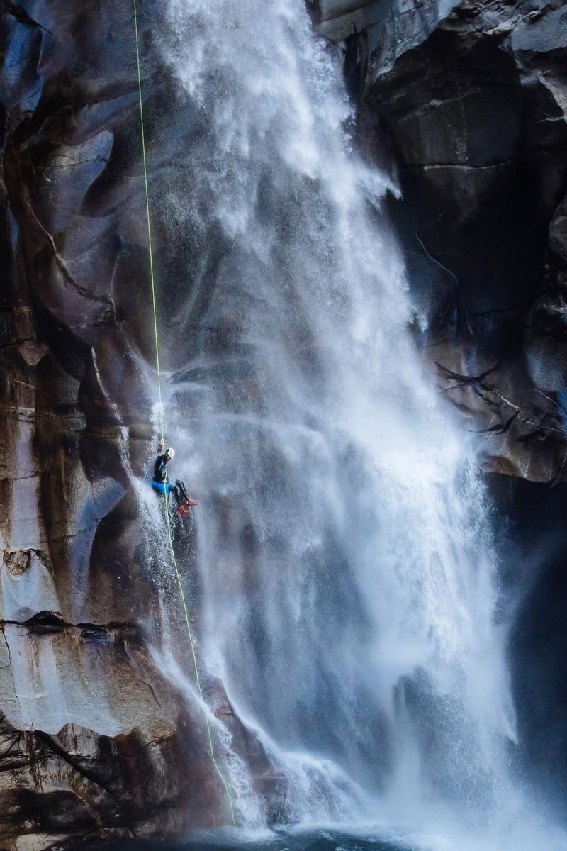 A person descending a waterfall using rappel techniques in Ticino, Switzerland