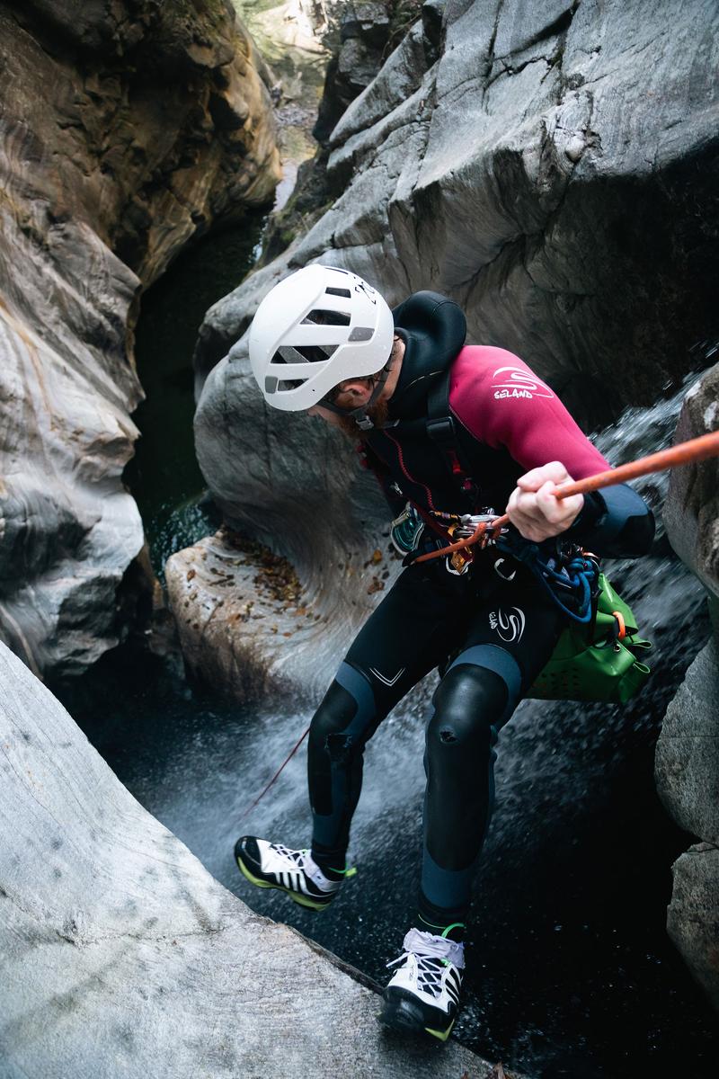 A close up shot of someone canyoning in a narrow gorge
